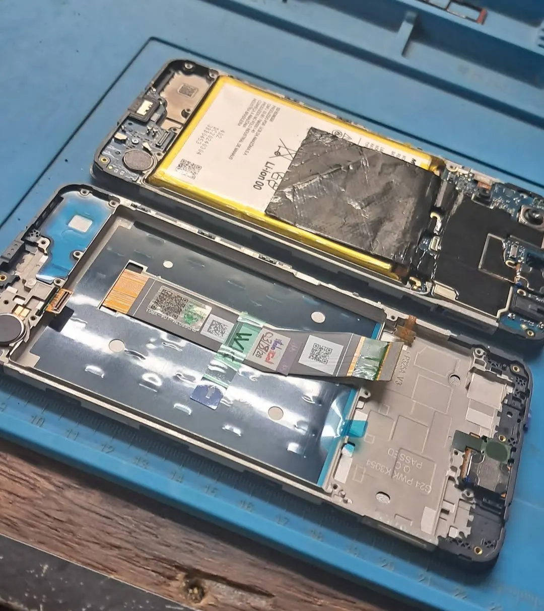 Celular aberto na bancada, com a bateria e os cabos à vista